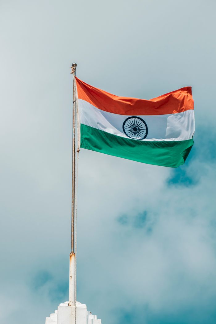Home The Indian national flag waving proudly against a cloudy blue sky in Puducherry.